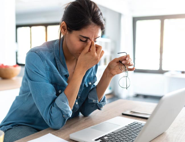 woman working at her computer in her home overwhelmed
